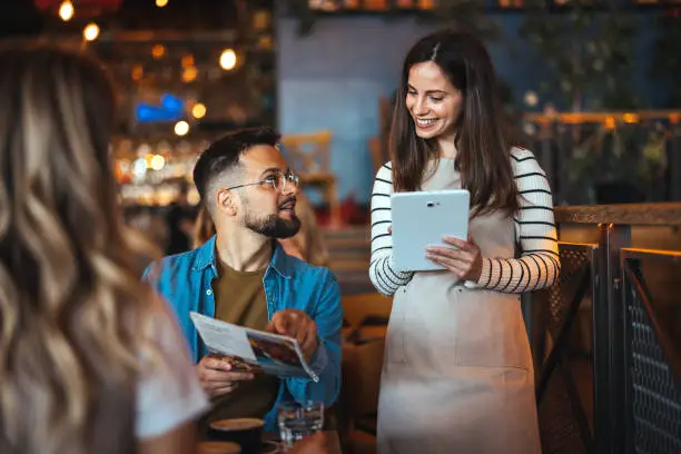Moza tomando un pedido con una tablet en un bar