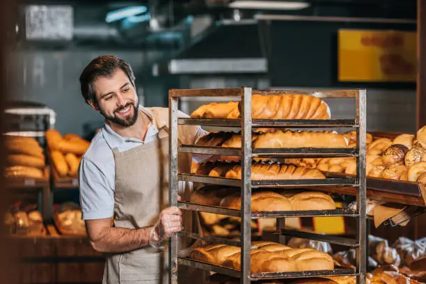 Panadero acomodando panes en el exhibidor de una panadería